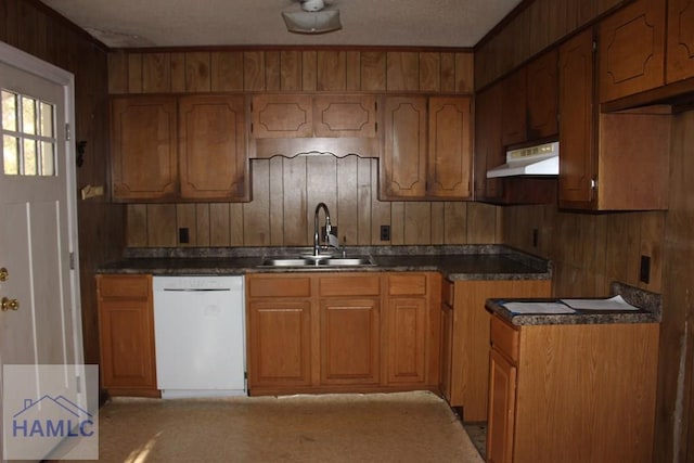 kitchen featuring dishwasher, stovetop, wooden walls, and sink