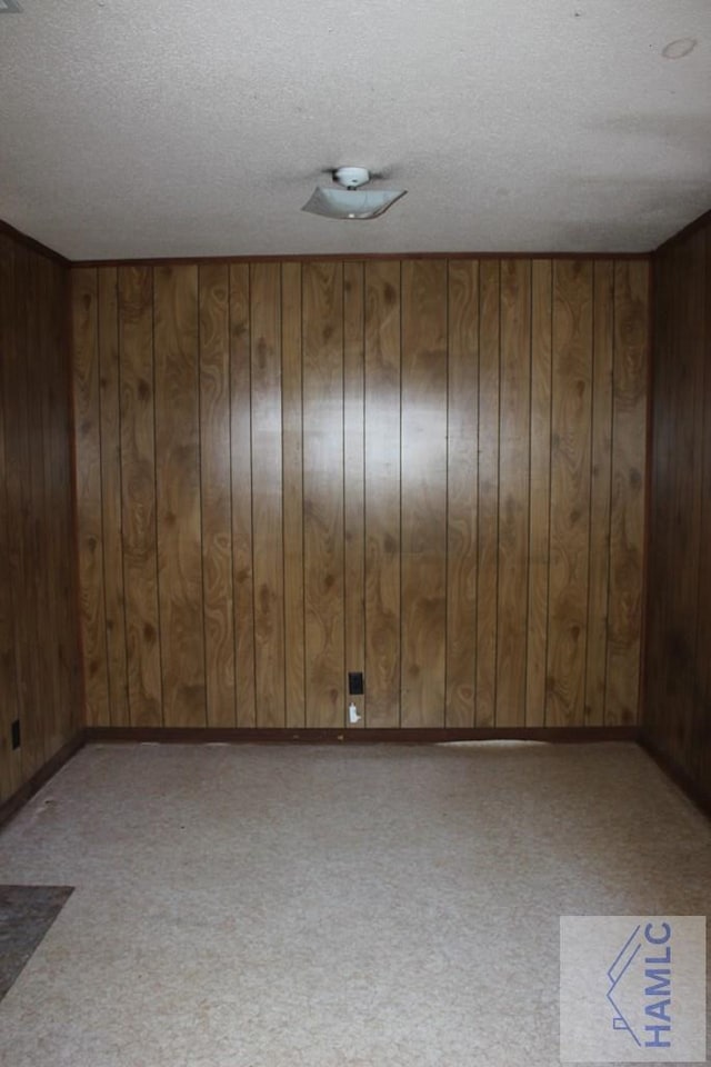 unfurnished room featuring wood walls and a textured ceiling