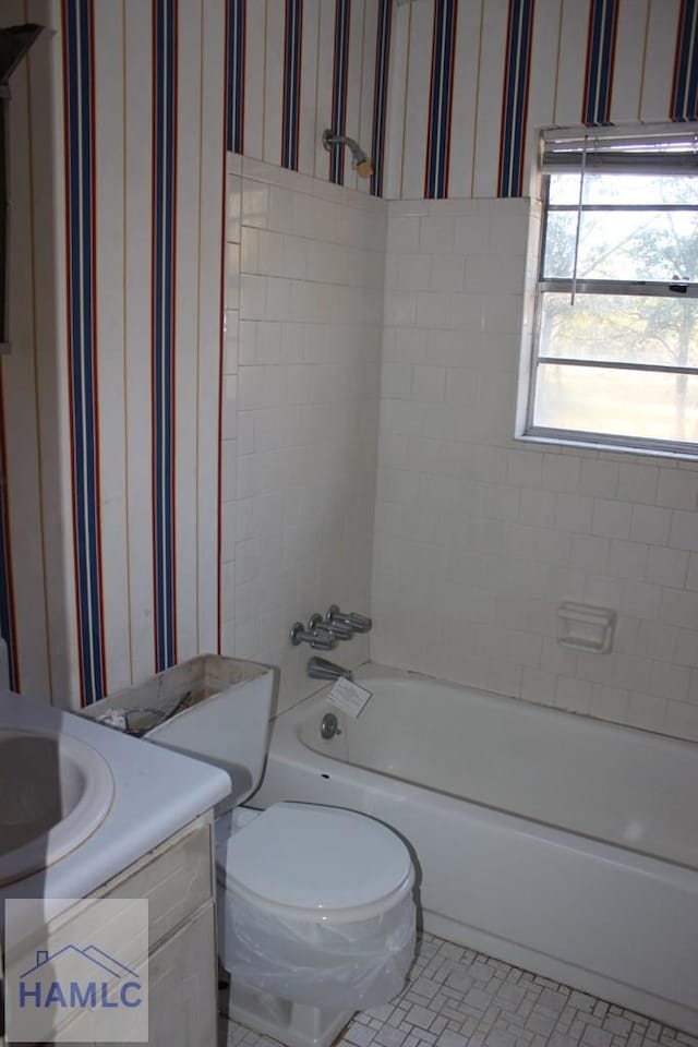 full bathroom with tile patterned flooring, vanity, tiled shower / bath combo, and toilet