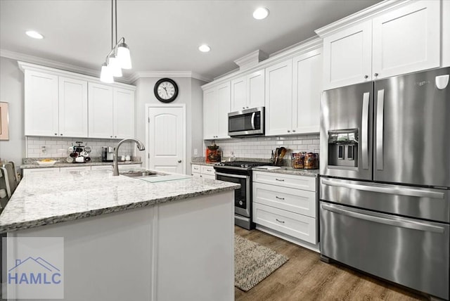 kitchen with white cabinets, crown molding, an island with sink, appliances with stainless steel finishes, and light stone counters