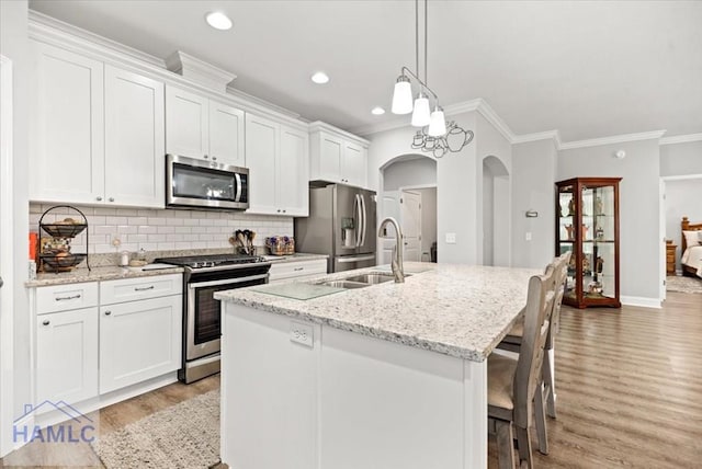 kitchen with a kitchen island with sink, light hardwood / wood-style flooring, appliances with stainless steel finishes, light stone counters, and white cabinetry