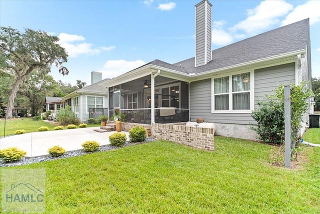 rear view of house featuring a lawn and a sunroom