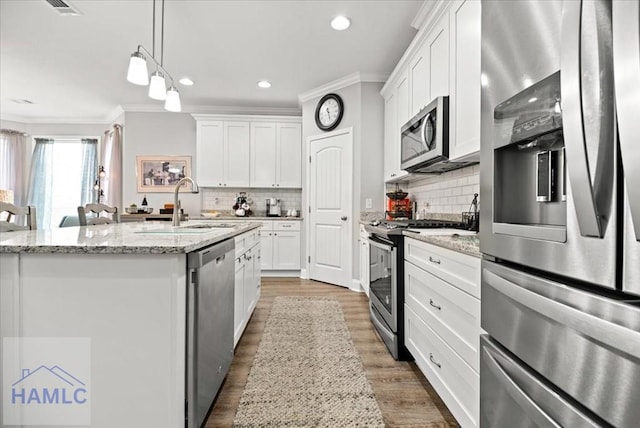 kitchen featuring light stone counters, white cabinetry, stainless steel appliances, and a kitchen island with sink