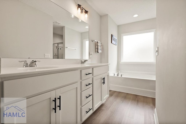 1201 Grayson Ave, Hinesville, GA 31313 - bathroom featuring double vanity, wood finished floors, a bath, a shower with shower door, and recessed lighting