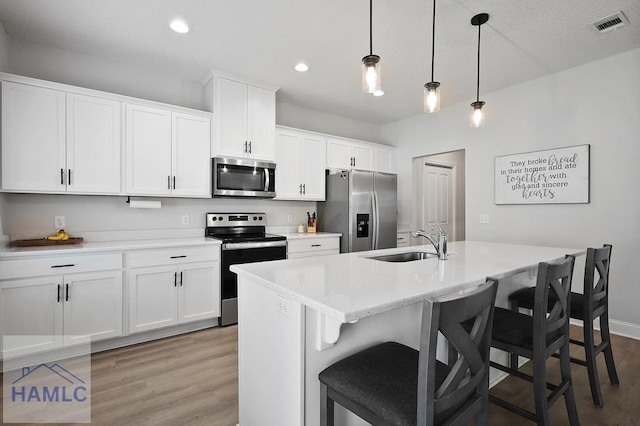 1201 Grayson Ave, Hinesville, GA 31313 - kitchen with stainless steel appliances, a sink, light wood-style floors, a breakfast bar, and white cabinetry
