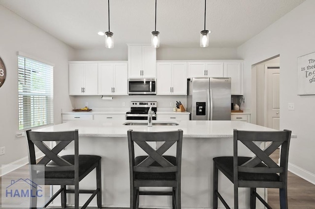 1201 Grayson Ave, Hinesville, GA 31313 - kitchen with appliances with stainless steel finishes, baseboards, white cabinets, hanging light fixtures, and dark wood finished floors