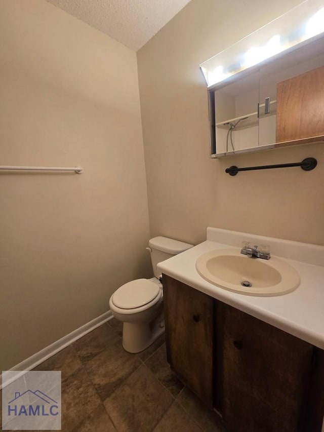 bathroom with a textured ceiling, vanity, and toilet