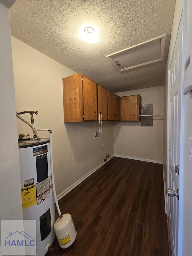 washroom with water heater, dark hardwood / wood-style flooring, a textured ceiling, and cabinets