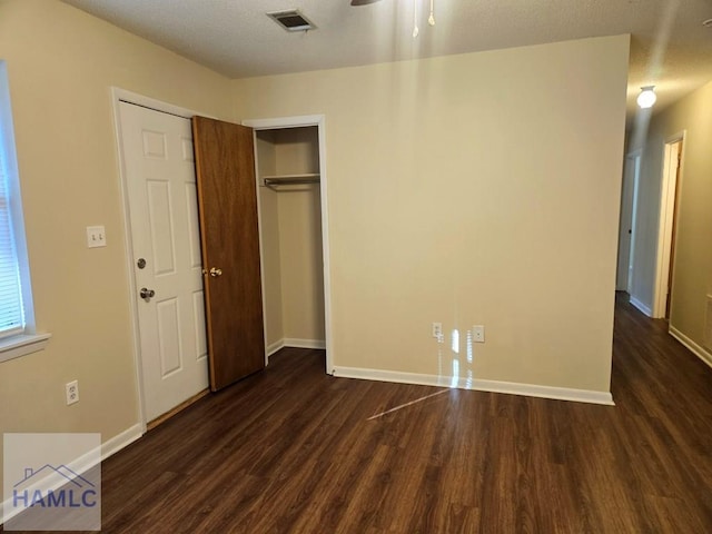 unfurnished bedroom featuring dark hardwood / wood-style flooring, a closet, and a textured ceiling