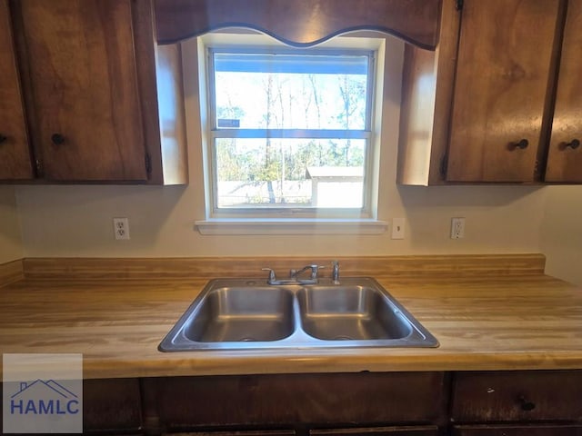 kitchen featuring sink, dark brown cabinets, and wood counters