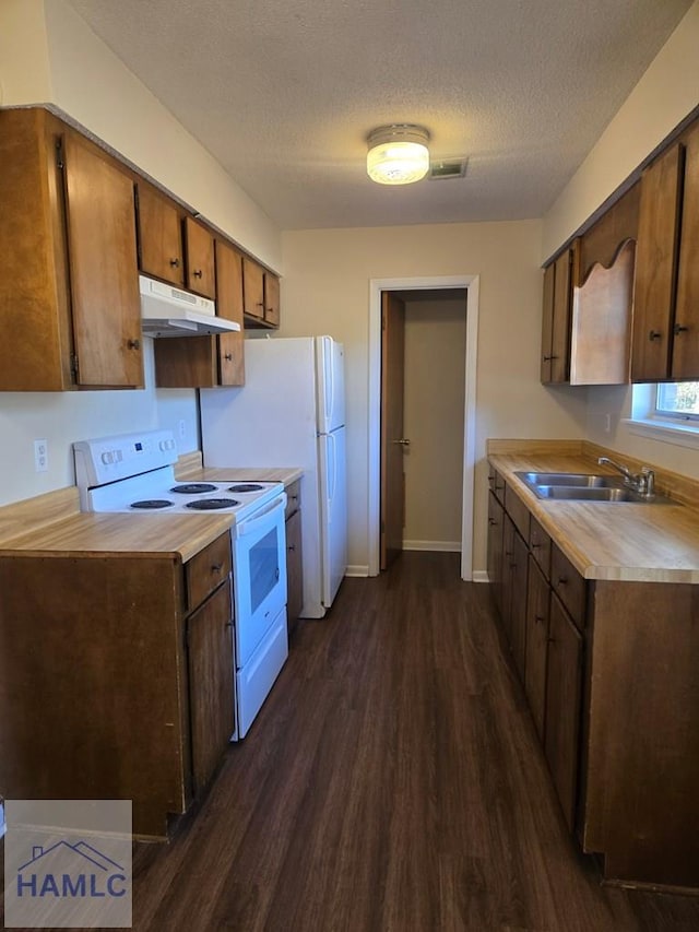 kitchen featuring white appliances, dark hardwood / wood-style floors, a textured ceiling, and sink