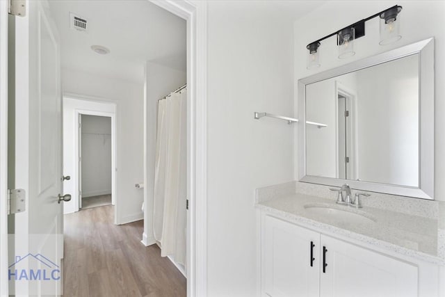 bathroom featuring baseboards, visible vents, wood finished floors, and vanity