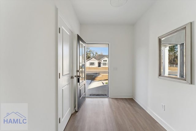 doorway to outside with wood finished floors and baseboards