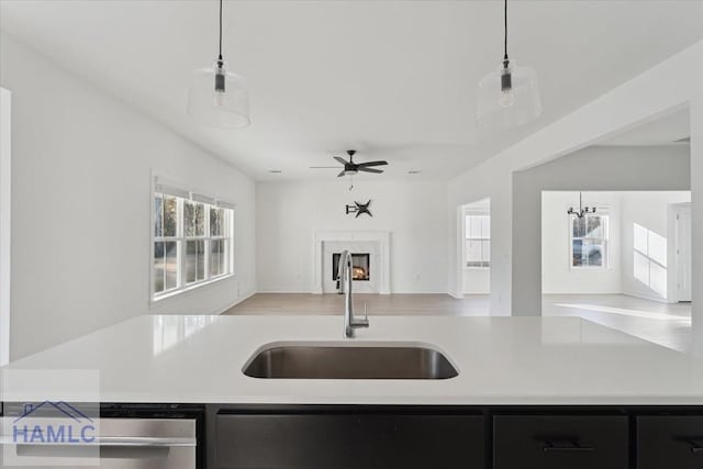 kitchen with a premium fireplace, a sink, open floor plan, light countertops, and dark cabinetry