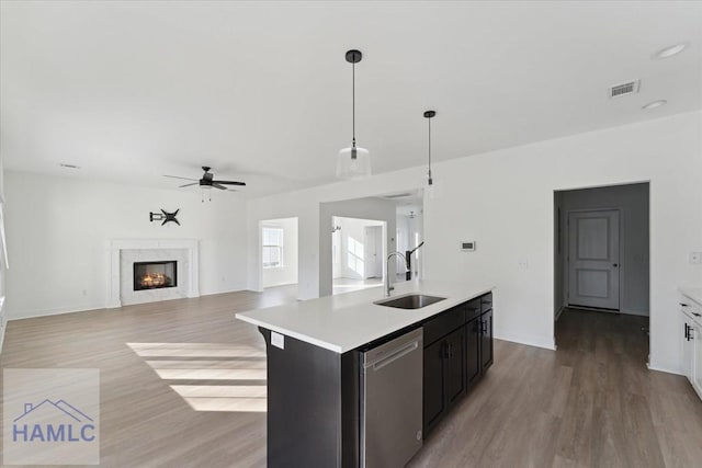 kitchen with a sink, visible vents, a high end fireplace, light countertops, and stainless steel dishwasher