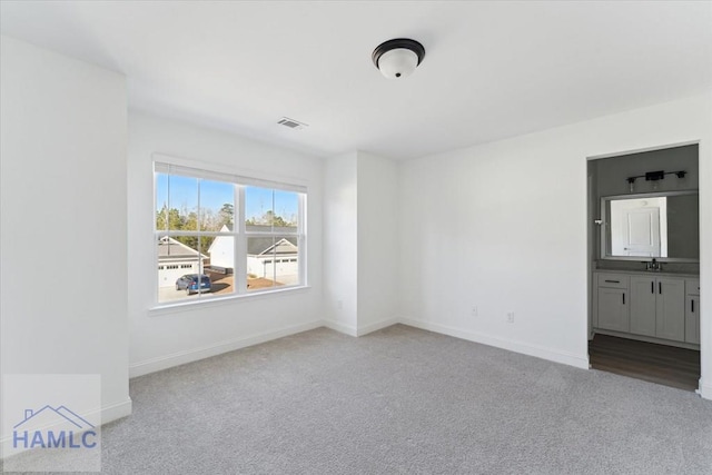 unfurnished bedroom with connected bathroom, carpet flooring, visible vents, and baseboards