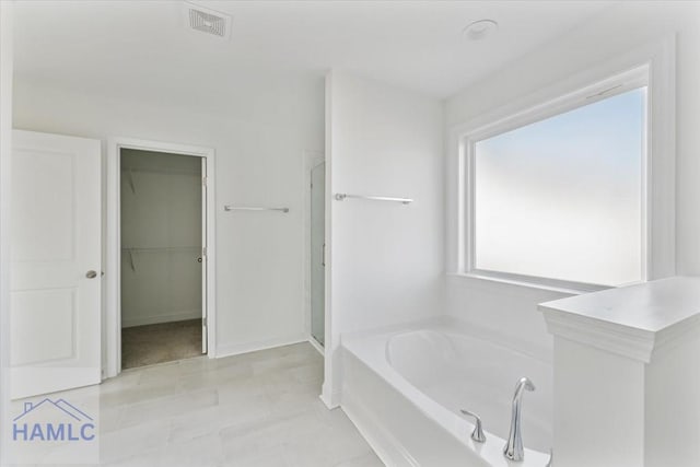 bathroom with a walk in closet, a garden tub, visible vents, a shower stall, and tile patterned floors