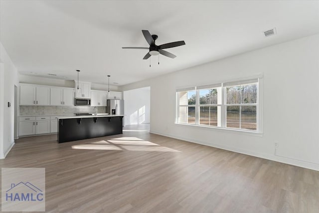 kitchen with open floor plan, stainless steel appliances, visible vents, and light wood-style floors