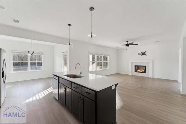 kitchen featuring a fireplace, stainless steel appliances, visible vents, open floor plan, and a sink