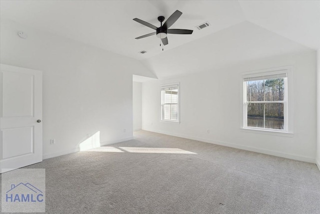 carpeted spare room with vaulted ceiling, baseboards, visible vents, and a ceiling fan