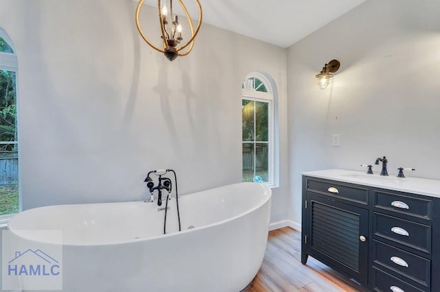 bathroom with a bathtub, wood-type flooring, vanity, and a chandelier