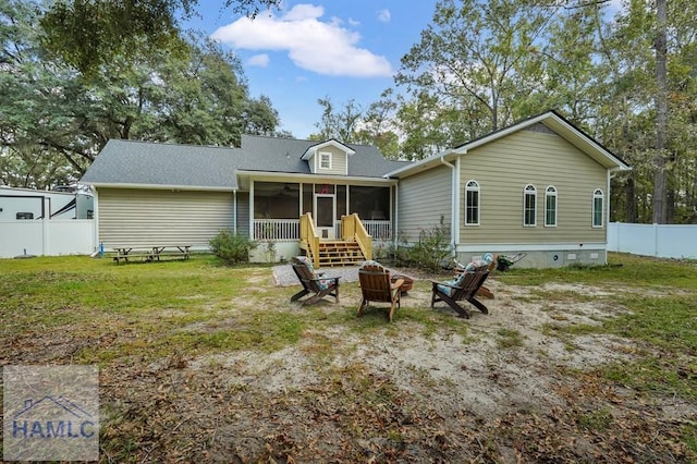 back of property with a sunroom, a fire pit, and a yard