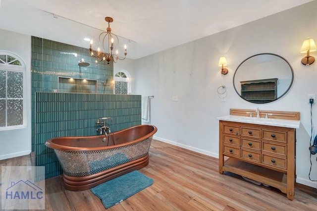 bathroom featuring a bathing tub, hardwood / wood-style floors, vanity, and an inviting chandelier