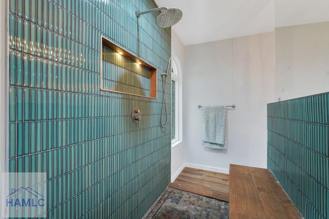 bathroom with a shower, wood-type flooring, and tile walls