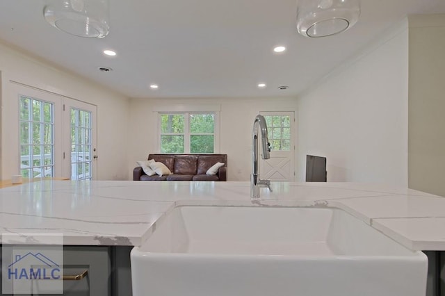 kitchen featuring recessed lighting, open floor plan, light stone countertops, and a sink