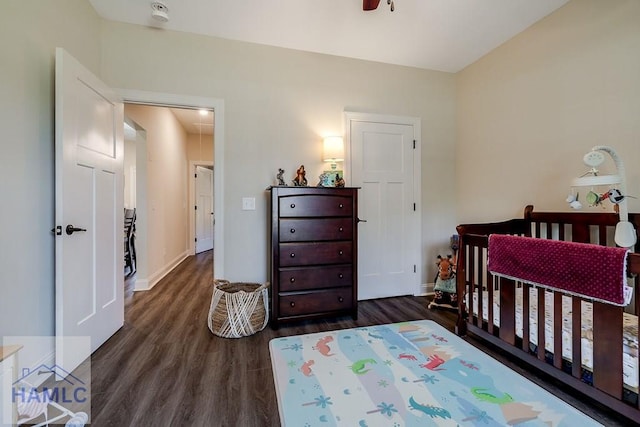 bedroom with attic access, a crib, baseboards, and wood finished floors