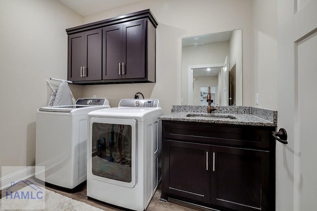 washroom with washer and clothes dryer, light wood-type flooring, a sink, and cabinet space