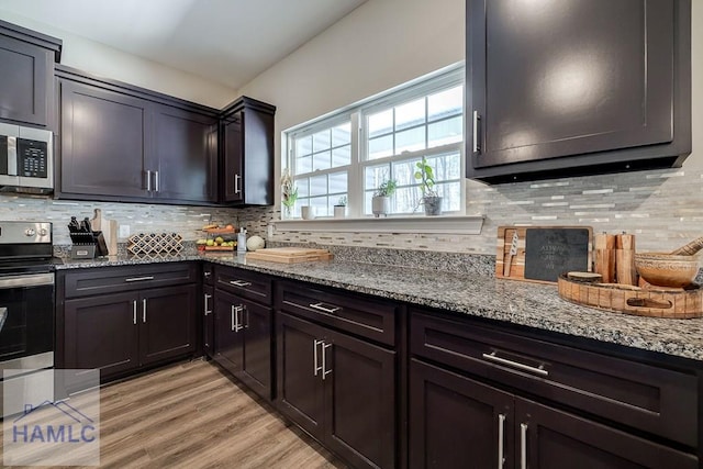 kitchen with light wood-type flooring, tasteful backsplash, light stone counters, and stainless steel appliances