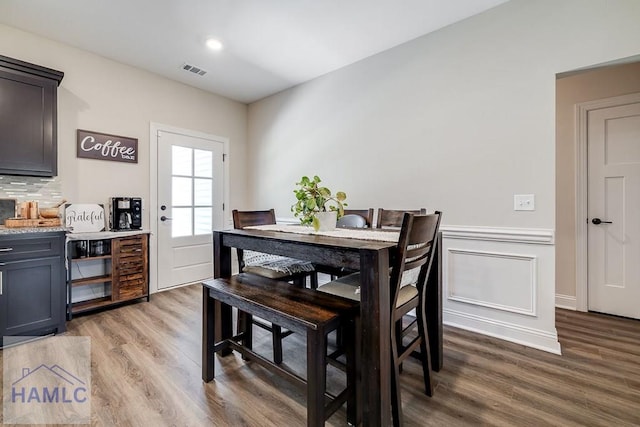 dining room featuring recessed lighting, a decorative wall, visible vents, wainscoting, and light wood finished floors