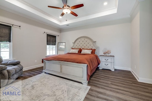 bedroom featuring crown molding, multiple windows, a raised ceiling, and wood finished floors