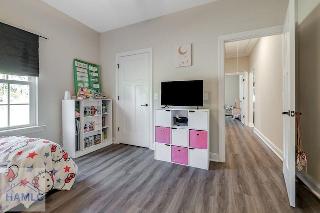 bedroom with wood finished floors, attic access, and baseboards