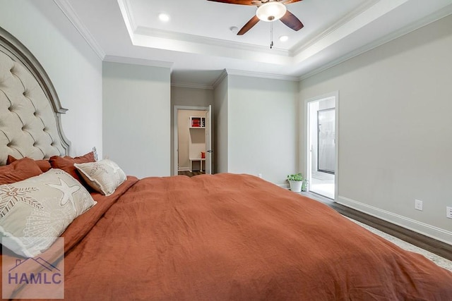 bedroom with a tray ceiling, crown molding, and wood finished floors