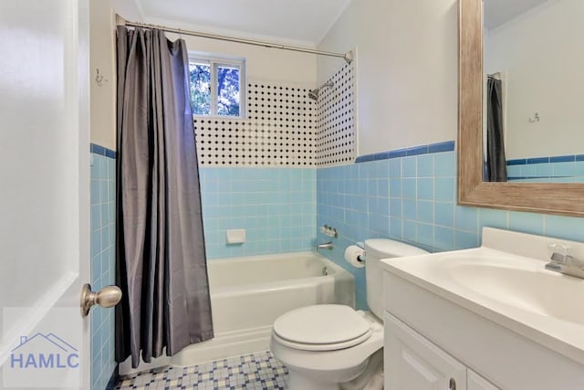 full bathroom with tile patterned flooring, toilet, shower / bath combo with shower curtain, vanity, and tile walls