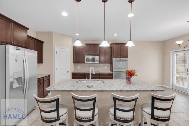23 Veranda Trl, Midway, GA 31320 - kitchen with stainless steel appliances, light tile patterned floors, backsplash, an island with sink, and dark brown cabinets
