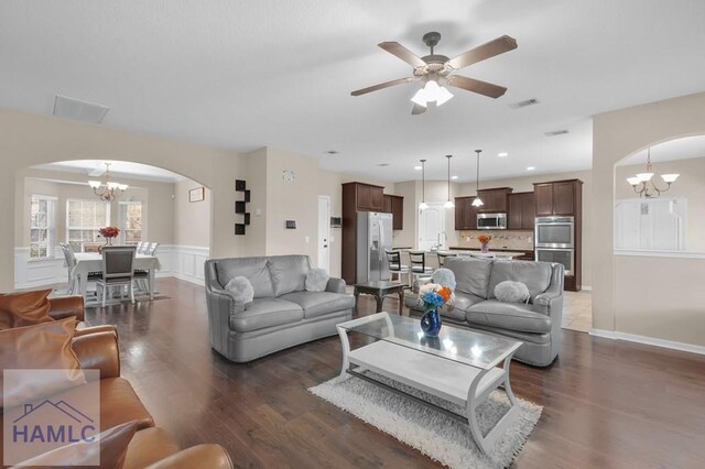 23 Veranda Trl, Midway, GA 31320 - living area featuring arched walkways, a chandelier, dark wood-style floors, a ceiling fan, and a wainscoted wall