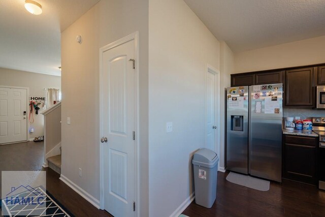 kitchen featuring appliances with stainless steel finishes, dark wood-style flooring, dark brown cabinetry, and baseboards