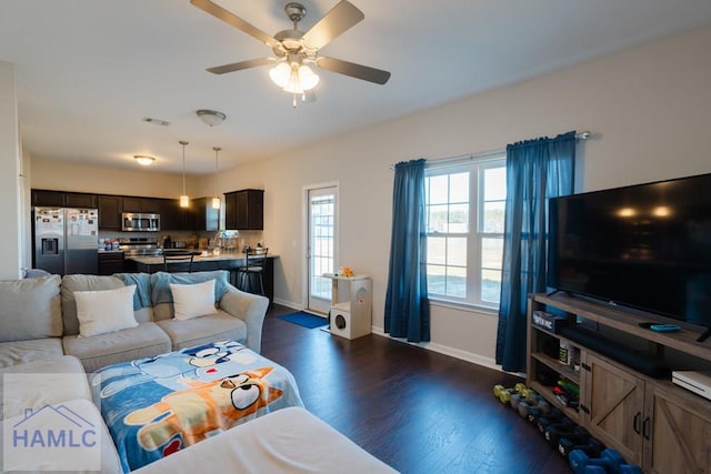 living room featuring ceiling fan, dark wood-style flooring, visible vents, and baseboards