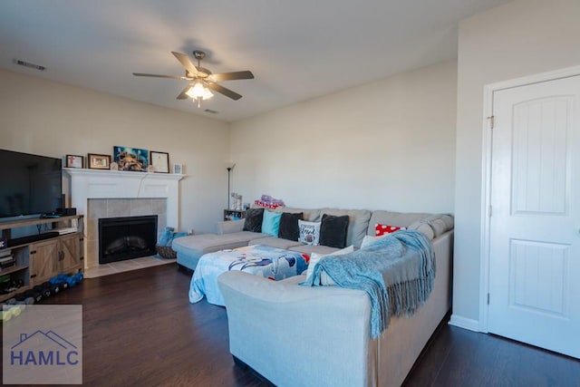 living area featuring ceiling fan, dark wood-style flooring, a fireplace, and visible vents