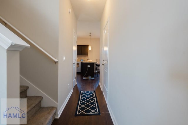 corridor featuring stairs, baseboards, and dark wood finished floors