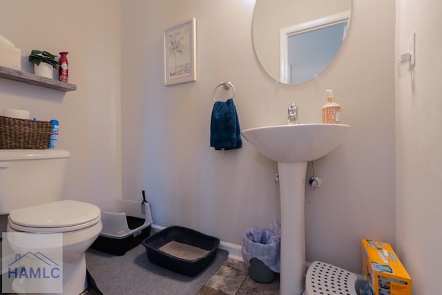 bathroom with toilet, baseboards, and tile patterned floors