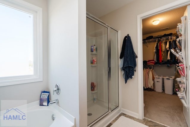 bathroom featuring a garden tub, a shower stall, and a walk in closet