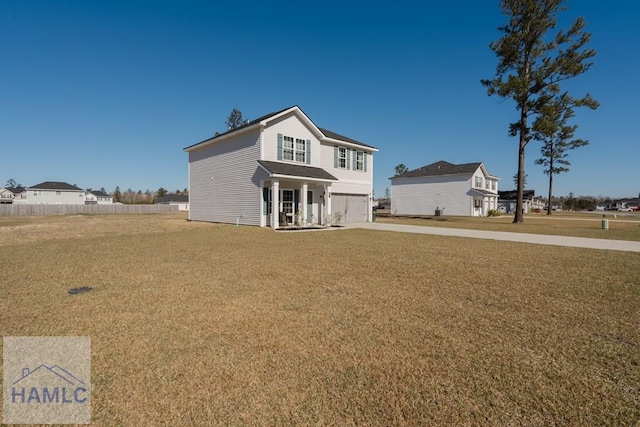 traditional-style home with an attached garage, driveway, a front yard, and fence