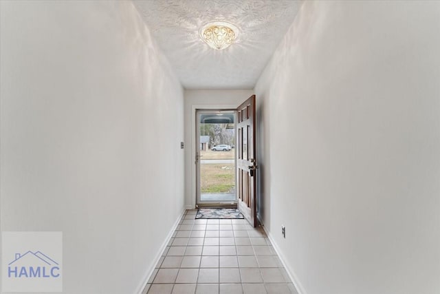 entryway with light tile patterned flooring, a textured ceiling, and baseboards