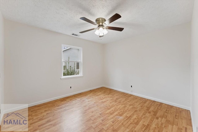 empty room featuring visible vents, baseboards, a ceiling fan, a textured ceiling, and light wood-style floors