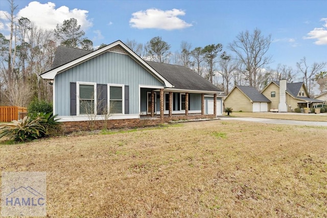 single story home with covered porch, fence, board and batten siding, and a front yard