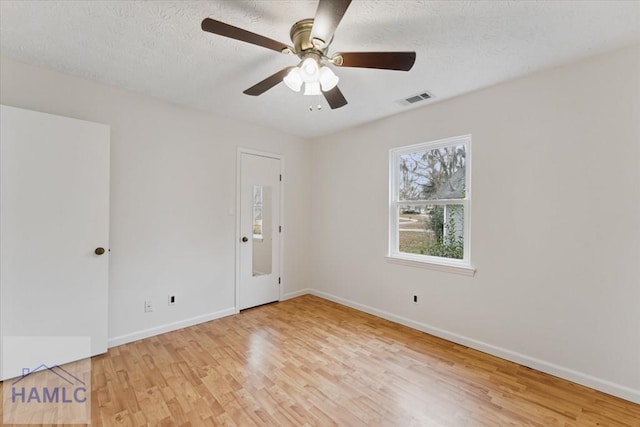 unfurnished room with a textured ceiling, ceiling fan, light wood-style flooring, visible vents, and baseboards